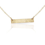 Gold initial bar necklace on model.