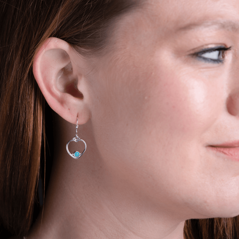 Heart turquoise earrings in silver on model.