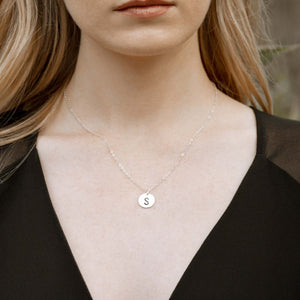 Initial silver disc necklace on model.